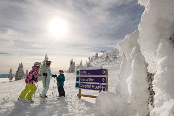 A skier with two children on the hills at Sun Peaks