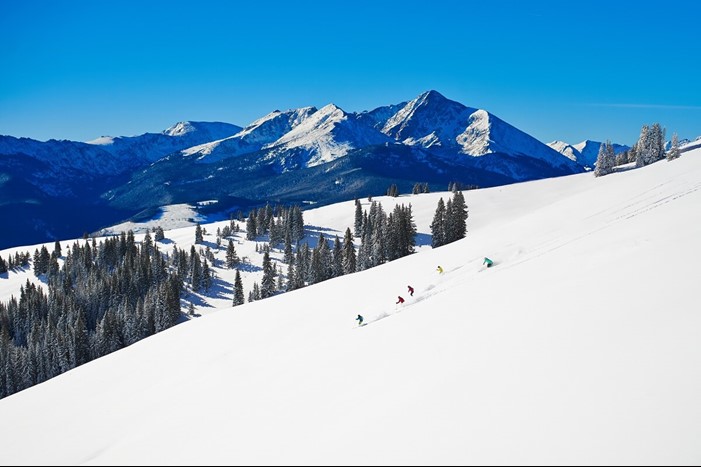 Group of skiers in Vail Ski Resort's back bowls on blue sky day