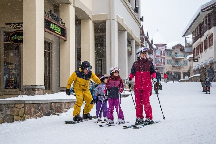Family skis through Sun Peaks village in winter