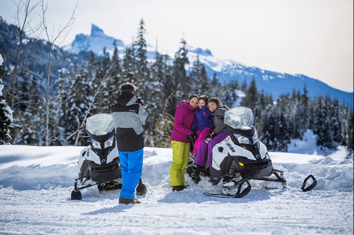Family takes a picture on a snowmobile tour at Whistler Blackcomb