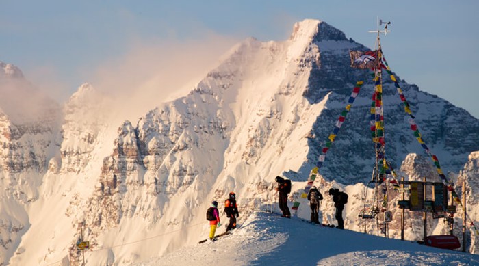 Group of skiers at the peak of Highland Bowl with Maroon Bells in the background