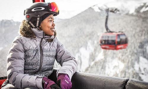 Woman in ski jacket looking out over the mountains on the Peak 2 Peak gondola