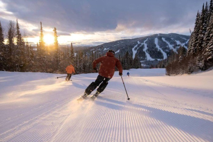 Two skiers gliding down the hill at Sun Peaks