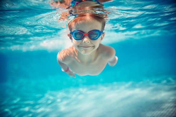 Kid under water with goggles on smiling