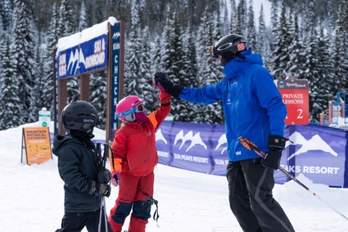 Photo of two children giving a ski instructor a high-five