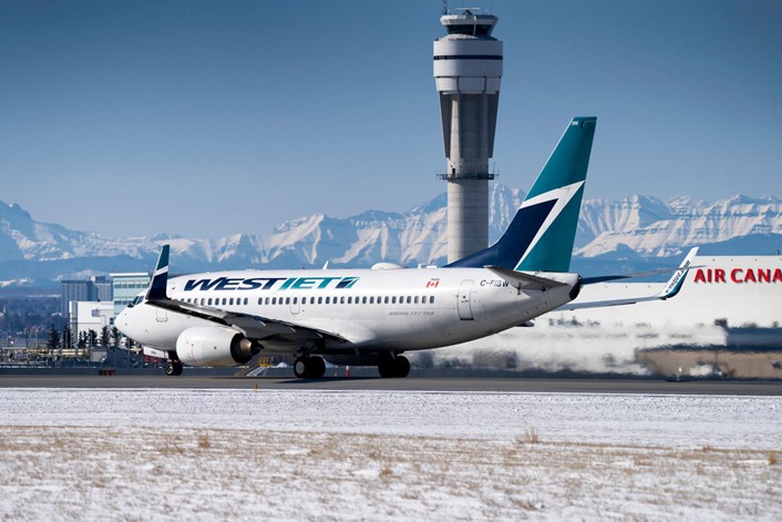 West Jet Plane on the tarmac at YYC with mountains behind it