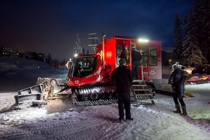 A photo of a snow cat machine on the snow in winter at night