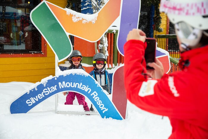 Two children getting a photo in front of a SilverStar Mountain Resort Sign