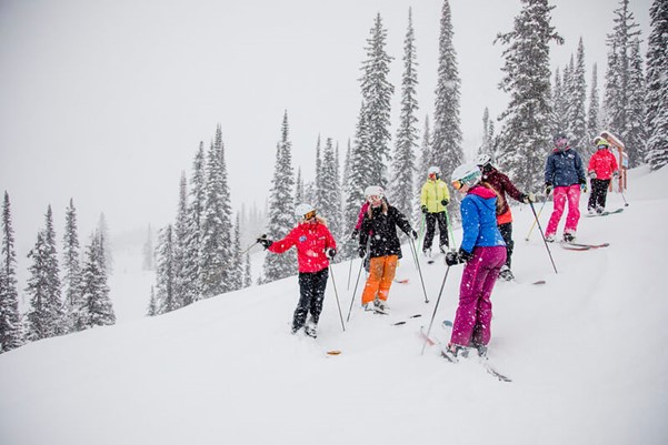 A group of people in snow school on the side of the mountain