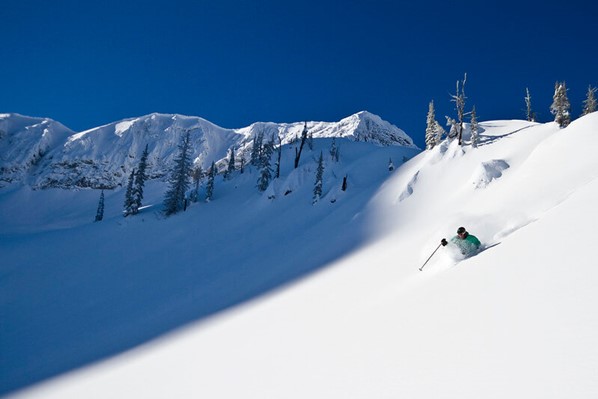 Person skiing down the side of a wide open, fresh mountainside