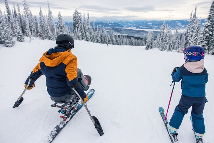 A ski instructor on a ski hill with a child learning to ski