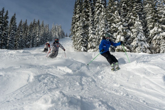 Three people skiing down a mountain at Sun Peaks