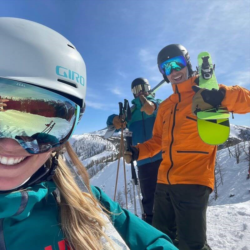 A selfie of a skier and two snowboarders standing on a ski hill.