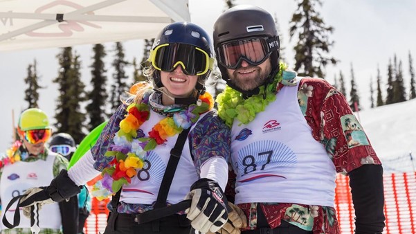 Two people dressed in Hawaiian gear at the bottom of a ski hill