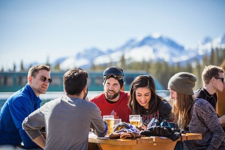 Group of friends around a picnic table with mountains behind them