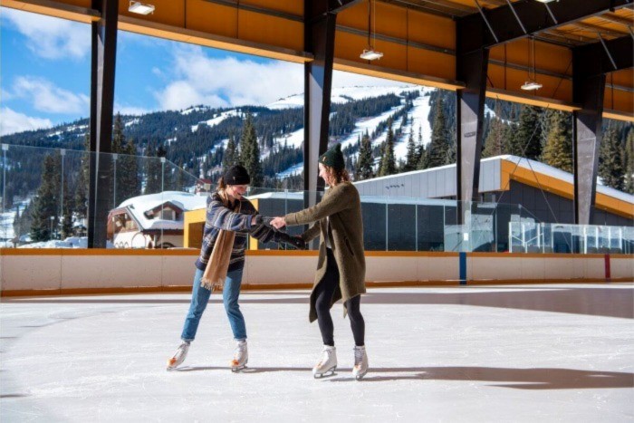 Two women skating at the rink at Sun Peaks