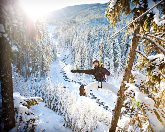 Woman on winter zipline above the forest in Whistler
