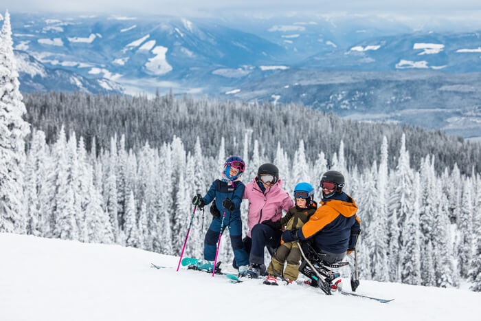 Family of four posing on a ski hill in the winter