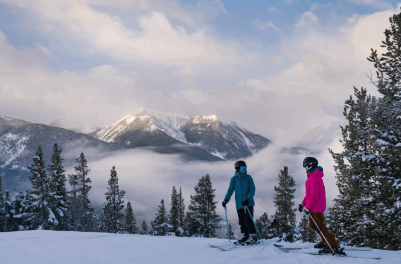 A photo of two skiers stopped at the top of a ski hill at Panorama Mountain Resort.